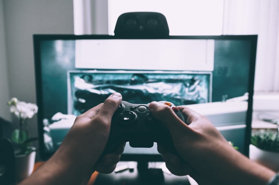 A person holds a video game controller in front of a TV