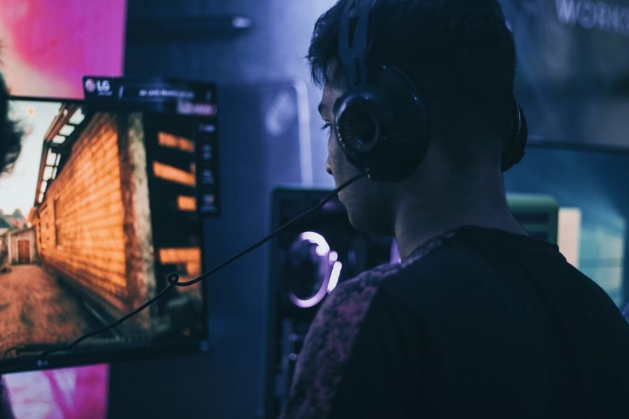 A man sits at a gaming PC with headphones on